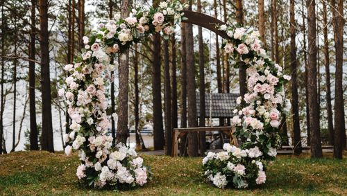 Свадебная арка, украшенная цветами, среди деревьев